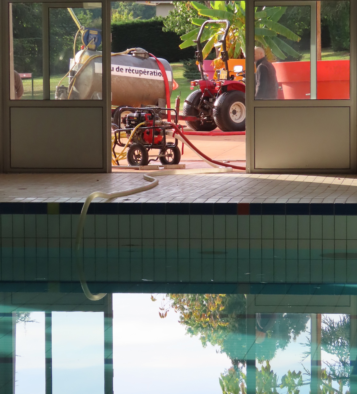 Un petit camion citerne récupérant l'eau d'une piscine pour arroser des plantations.