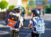 Deux enfants roulant sur leurs trottinettes dans une rue calme.