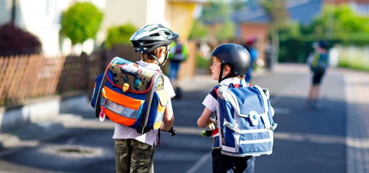 Deux enfants roulant sur leurs trottinettes dans une rue calme.